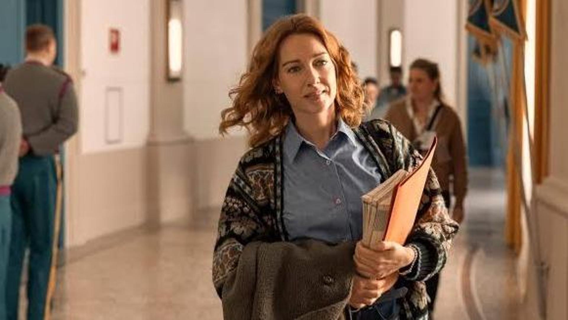 Attrice in uniforme davanti a un edificio storico con studenti militari