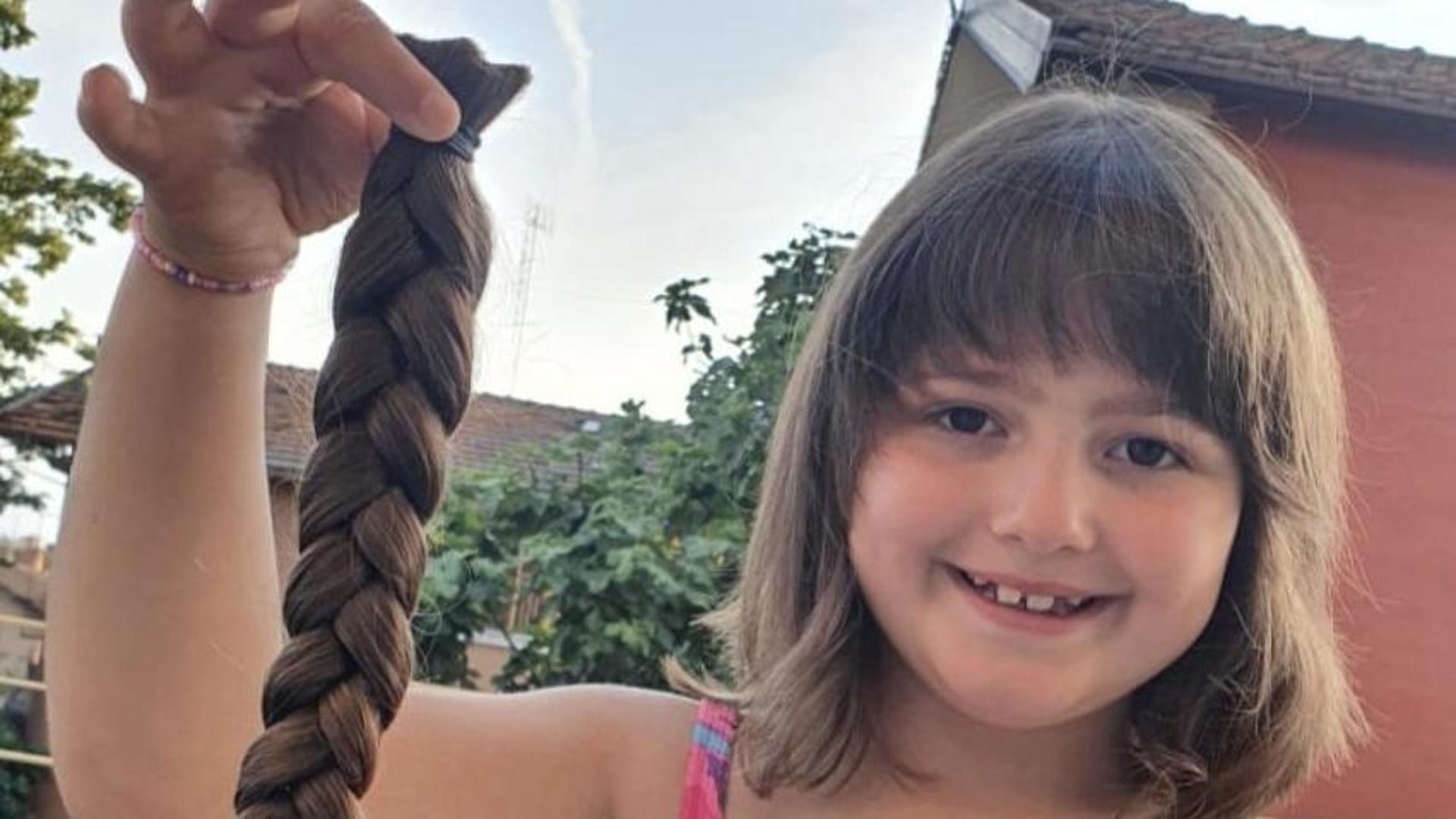 Bambina con capelli scuri e sorriso dolce dona trecce per aiutare malati di cancro