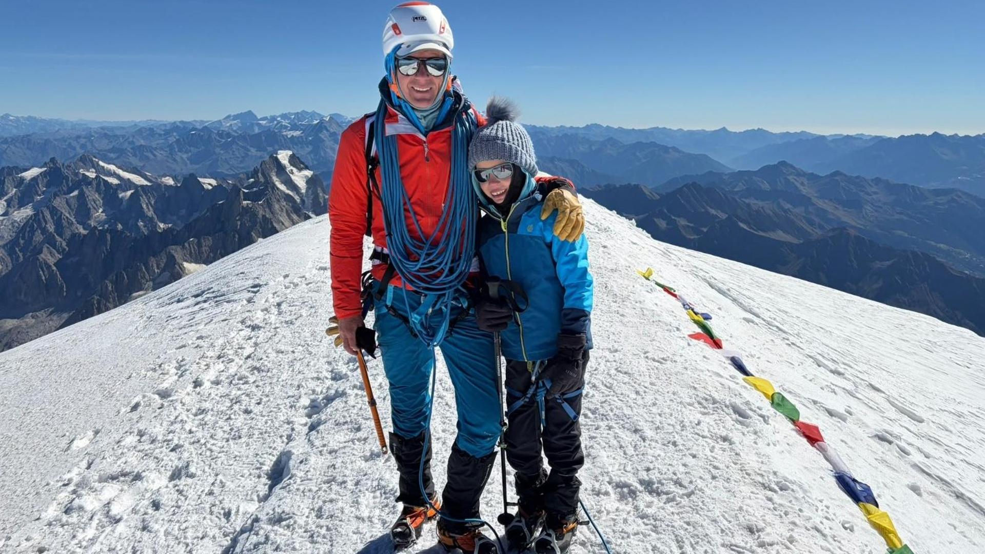 Bimbo in cordata sulla vetta del Monte Bianco, con padre al suo fianco, in un paesaggio innevato